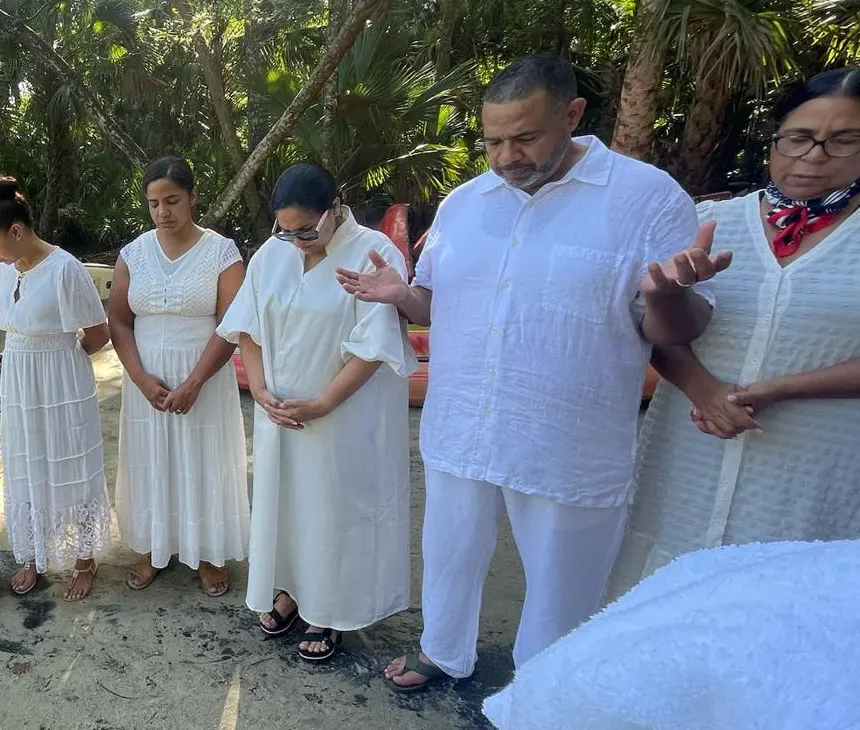 La congregación orando en la orilla antes de los bautismos